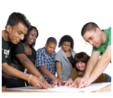 A group of people around a table all pointing to a large piece of paper.