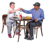 Two people having a meal together. They are clinking their glasses over a round table.