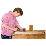 A person cuting a block of wood at a work bench.