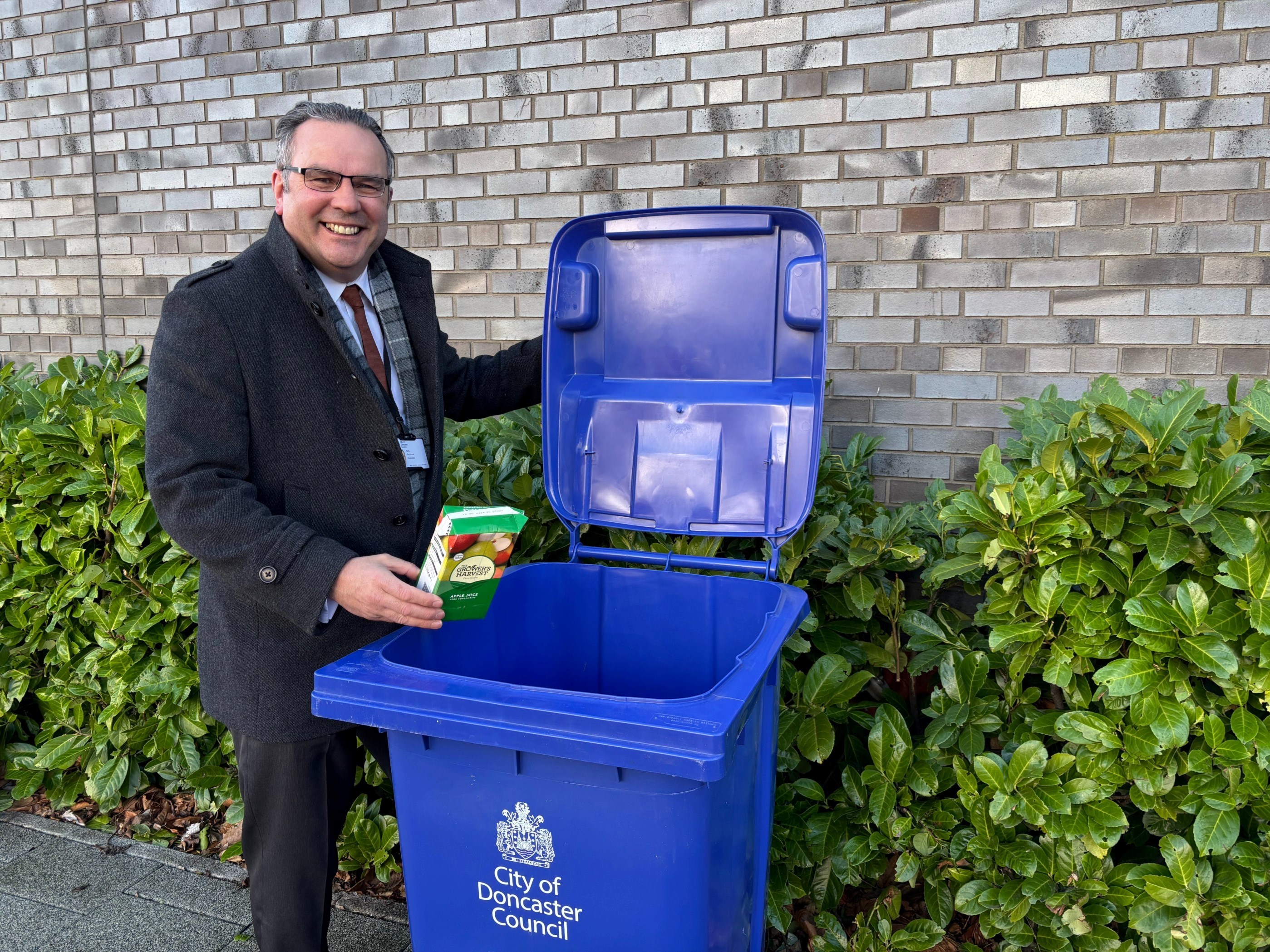 Cllr Houlbrook putting liquid carton in a blue bin 