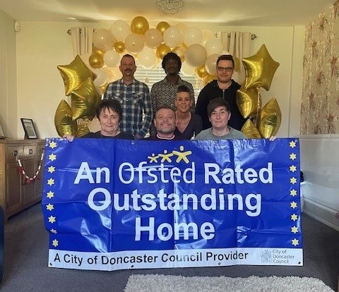 Pinewood Children's Home team are holding outstanding banner and celebrating success. 